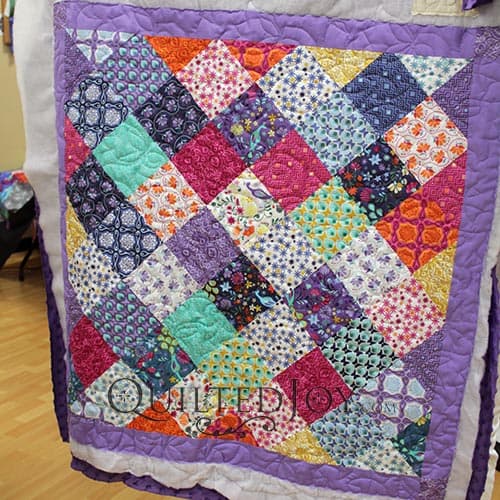 Sally's Charm Pack Quilt, quilting on a longarm quilting machine at Quilted Joy