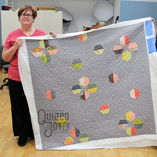 Peggy shows off her applique quilt after renting a longarm quilting machine at Quilted Joy