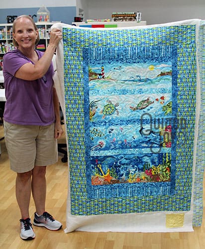 Jana shows off her sea life panel quilt after renting an APQS longarm quilting machine at Quilted Joy