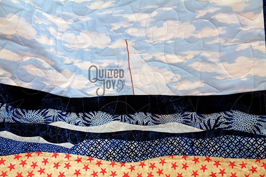 Karen shows off her appliqued beach quilt after longarm quilting it at Quilted Joy