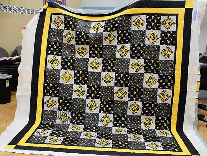 Falicia with her Iowa Hawkeye Quilt after quilting it on the longarm machines at Quilted Joy