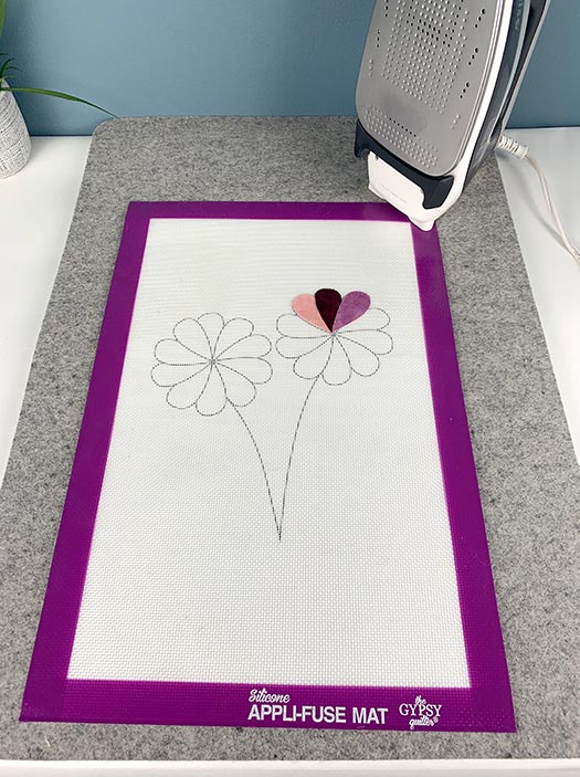 image of flowers drawn on a silicone appli-fuse mat with an iron in the background
