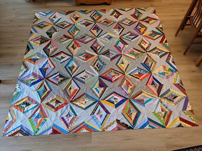 image of a colorful scrappy quilt on a floor