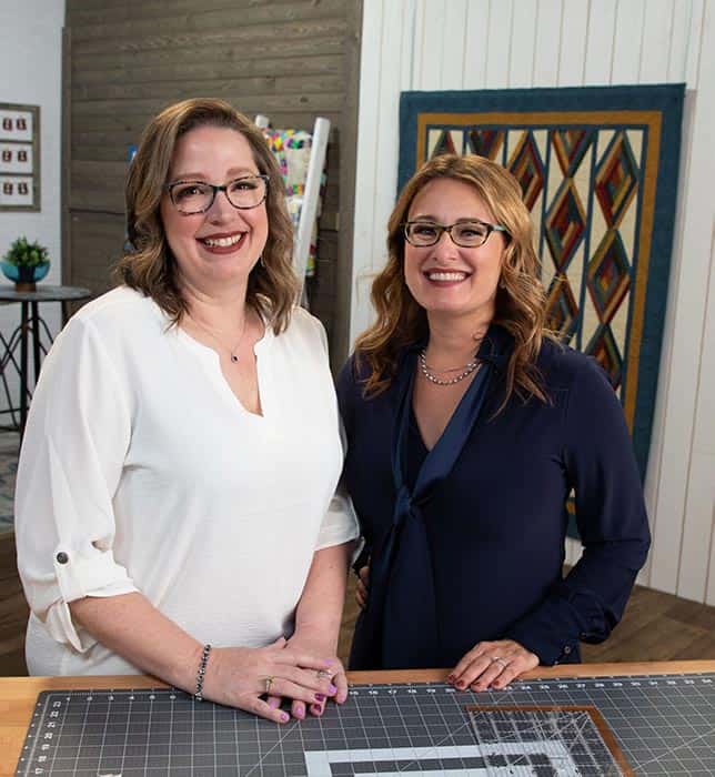 image of Angela Huffman and Sara Gallegos in front of the Cozy Moments Quilt on the Fons & Porter's Love of Quilting Show set