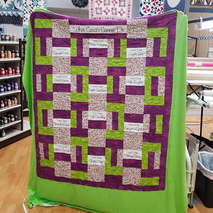 image of a green, purple, and pink quilt with motivational phrases about cancer