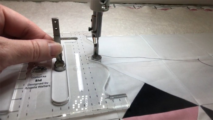 image of hands showing how to use the center cutout of the SID machine quilting ruler