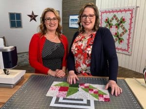image of Angela Huffman and Sara Gallegos on the set of Fons & Porter's Love of Quilting show with the Run for the Roses Quilt